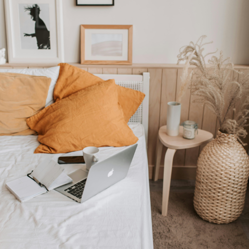 Empty bed with laptop and notebook